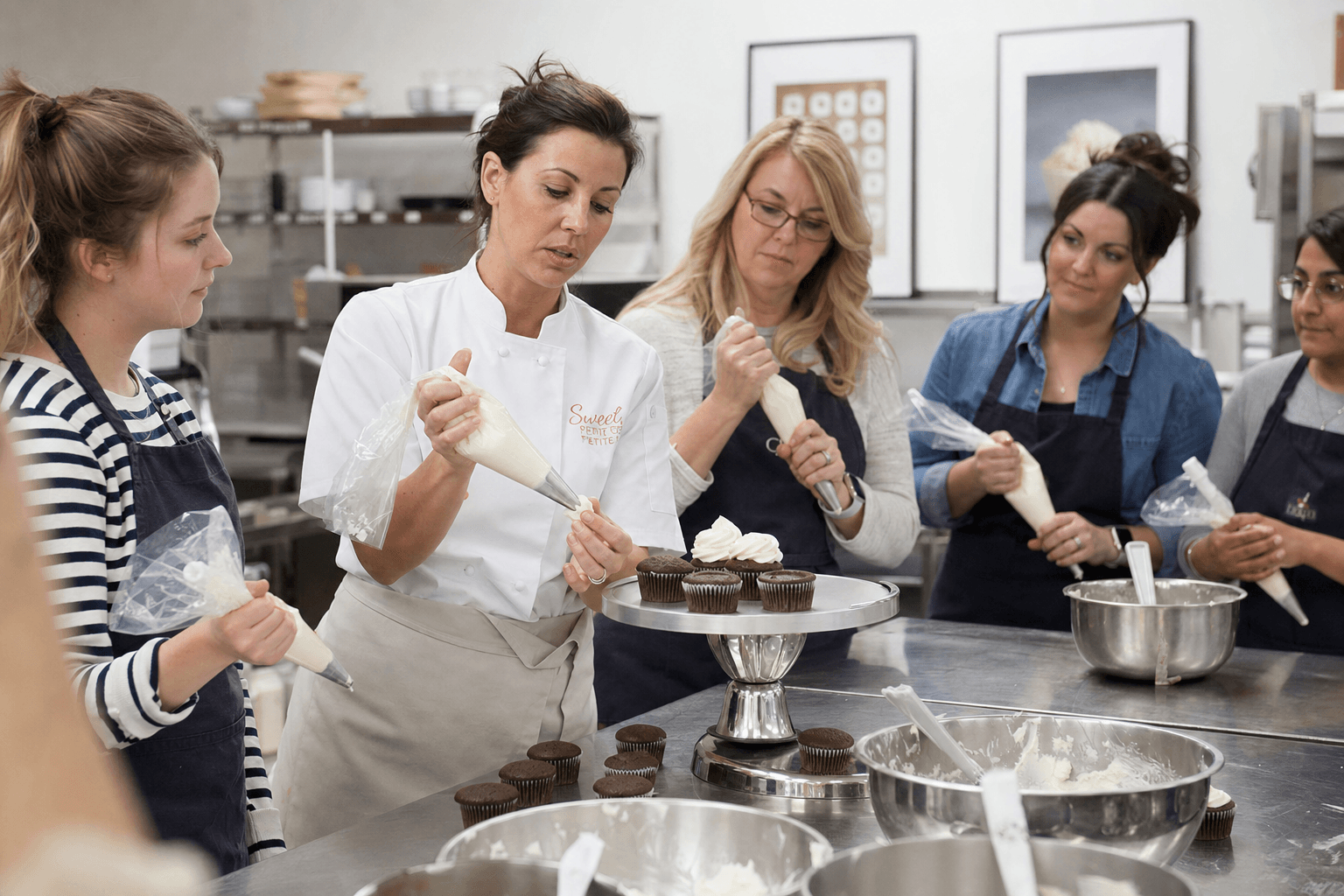 Bakery classroom with an instructor teaching cupcake decorating while students work at their stations
